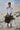 Young girl in ivory flower girl dress with lace sleeves, high-low hem, and floral basket-beach style wedding
