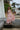 Girl in a pink two piece dress with ruffle detailing standing on wooden steps by a house with palm trees in the background