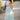 Girl wearing in a light green tow piece crop top and maxi sksirt with lace detailing standing on a path with blurred background